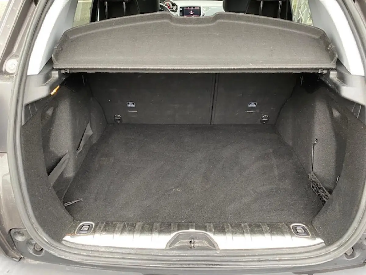 Coffre ouvert vu de l'arrière d'un Peugeot 2008 gris platinium, montrant un espace de chargement propre et spacieux.