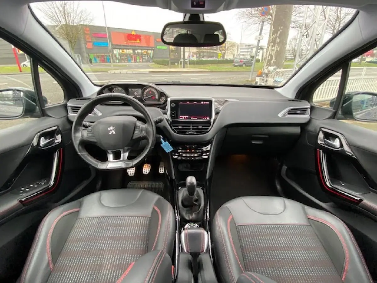Vue intérieure frontale du Peugeot 2008 GT Line 2017, montrant le volant, tableau de bord et sièges noirs avec surpiqûres rouges.