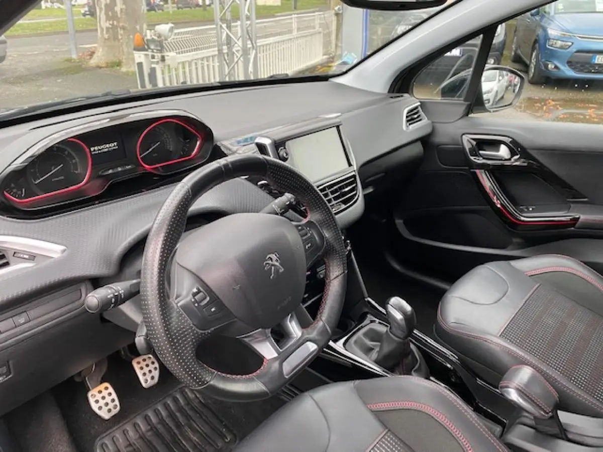 Vue intérieure côté conducteur du Peugeot 2008 GT Line 2017, volant cuir noir perforé avec surpiqûres rouges et pédalier aluminium sport.
