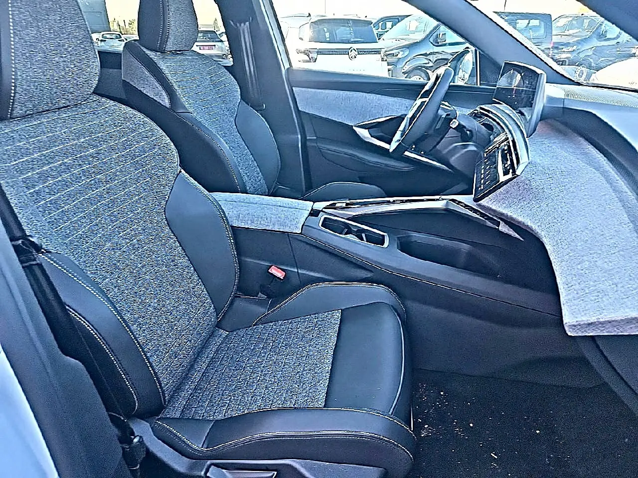 Vue intérieure côté conducteur du Peugeot 5008 Hybrid 145 allure e-dcs6 2025 avec sièges tissu et cuir noir et gris.