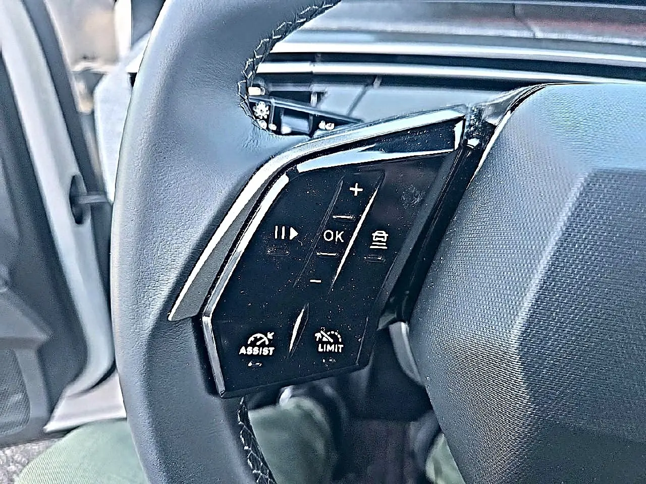Gros plan sur les commandes multifonctions du volant cuir noir du Peugeot 5008 Hybrid 145 allure e-dcs6 blanc.