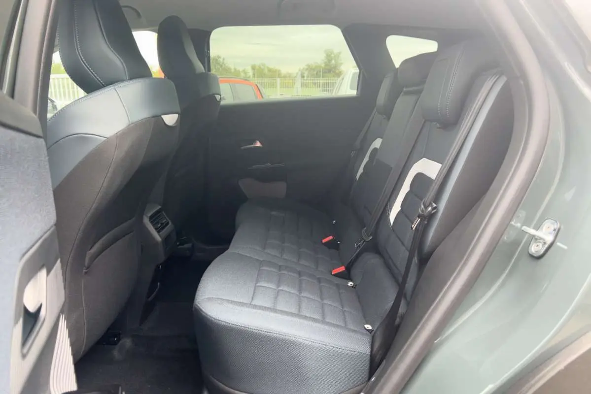 Vue côté gauche sur l'intérieur arrière du Citroën C5 Aircross Hybrid 145 Plus PK Drive vert Astoria avec sièges tissu gris.