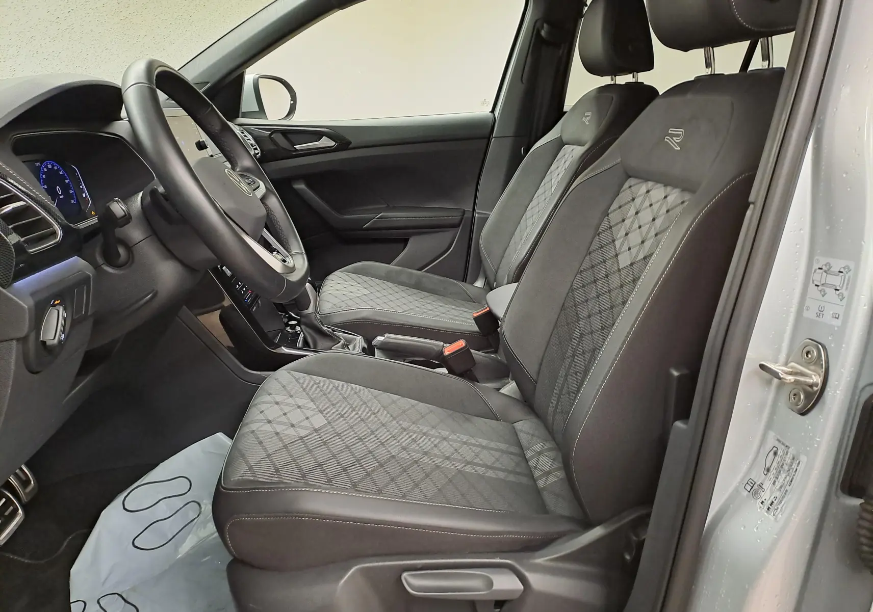 Vue intérieure côté gauche du Volkswagen T-Cross 2025 R-Line Edition, sièges noirs avec surpiqûres et logo R brodé.