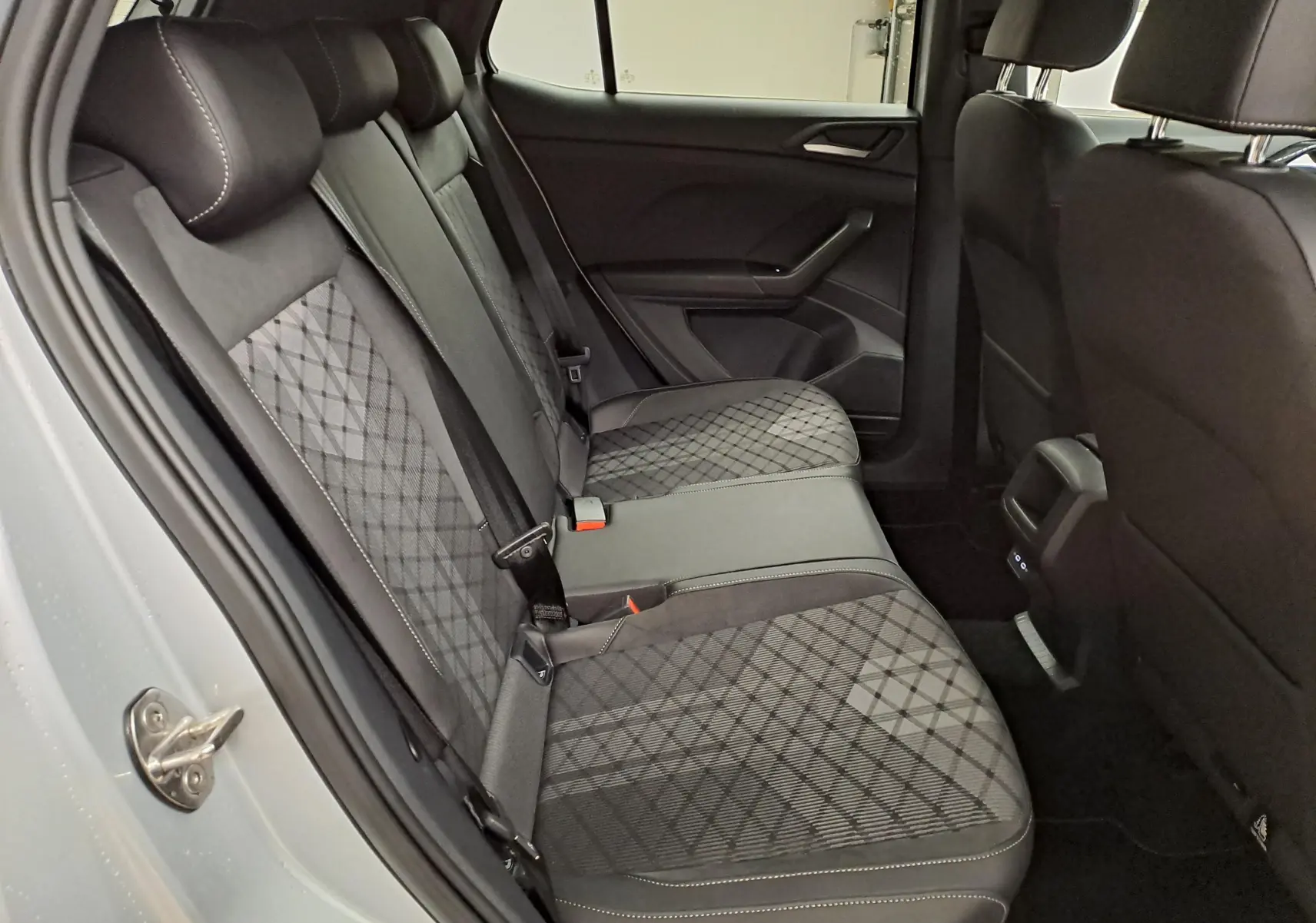 Vue intérieure côté gauche des sièges arrière du Volkswagen T-Cross 2025 R-Line Edition avec sellerie tissu noir à motifs.
