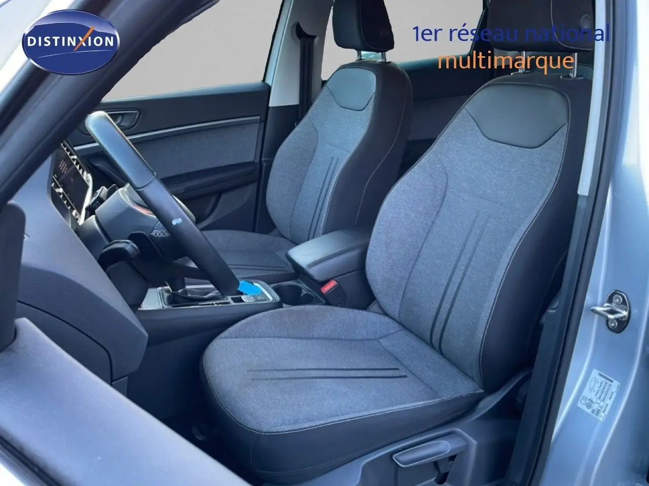 Vue intérieure côté conducteur du SEAT Ateca 2022 argent, sièges tissu gris avec contours noirs et volant multifonction.