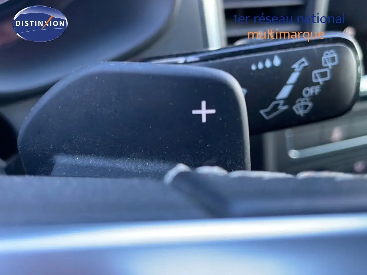Gros plan sur la palette de changement de vitesse "+" et le commodo de lève-glace dans l'habitacle d'un SEAT Ateca argent.