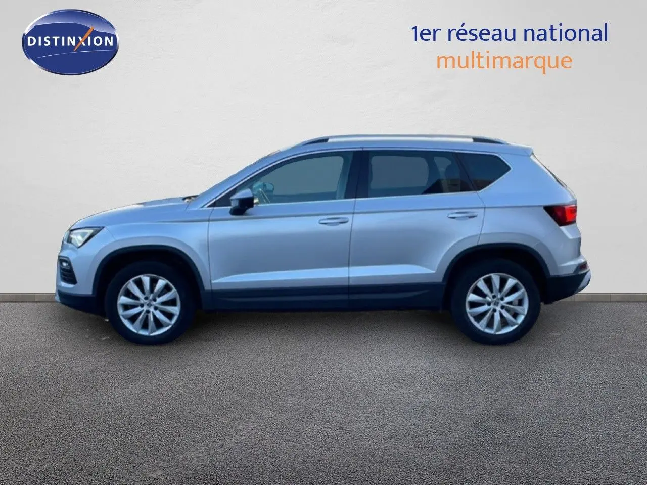 Vue de profil côté gauche d'un SEAT Ateca 2022 argent Reflex Metal avec jantes alliage et barres de toit.