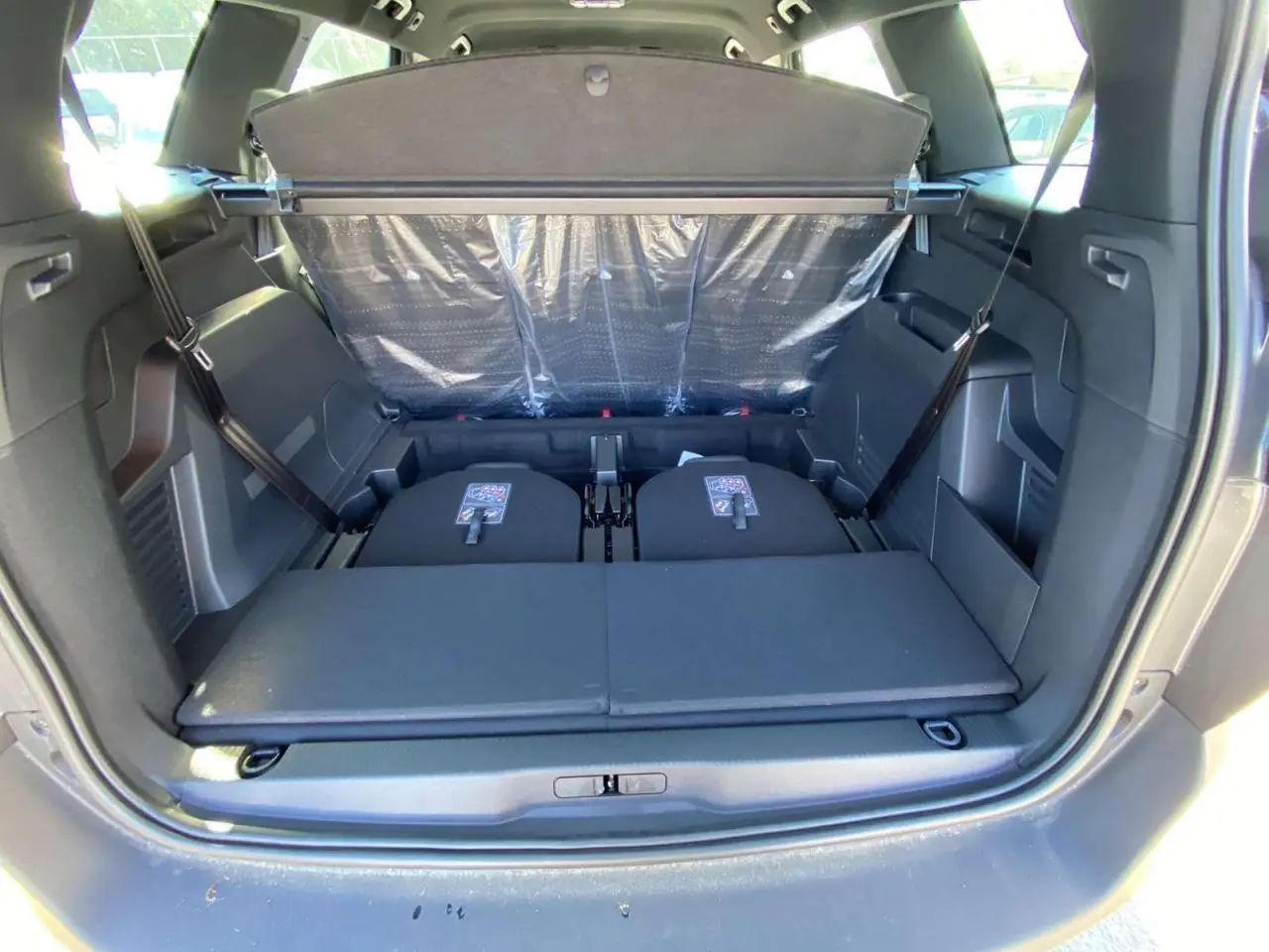 Coffre ouvert vu de l'arrière du Peugeot 5008 gris platinium avec banquette arrière partiellement rabattue.