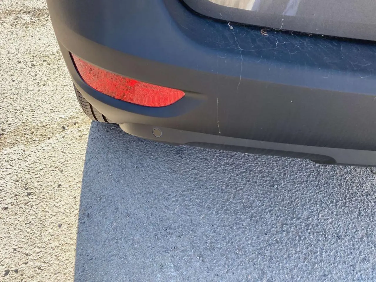 Gros plan sur le pare-chocs arrière gris platinium métallisé du Peugeot 5008 avec feu rouge et capteur de stationnement.