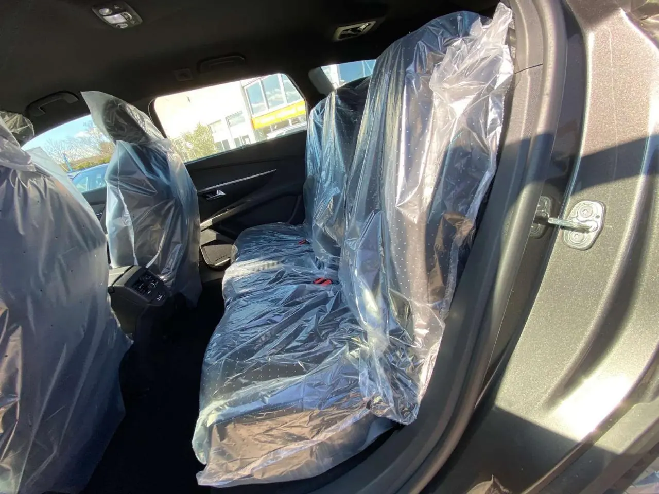 Vue intérieure côté droit des sièges arrière du Peugeot 5008 gris platinium métallisé, protégés par des housses plastiques.