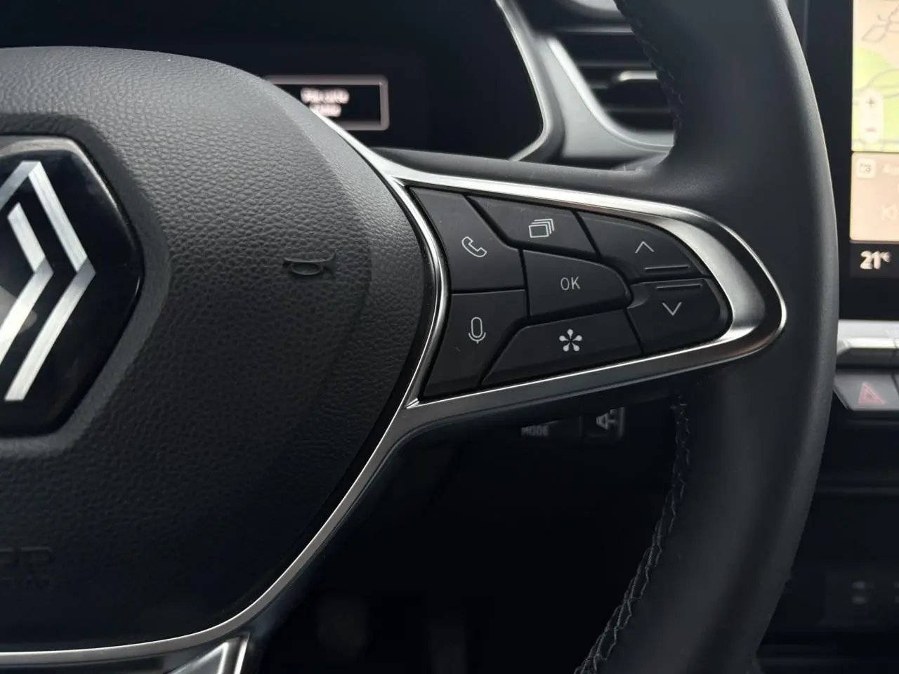 Gros plan sur le volant du Renault Captur TCE 100 Techno 2025, avec commandes intégrées et logo Renault visible.