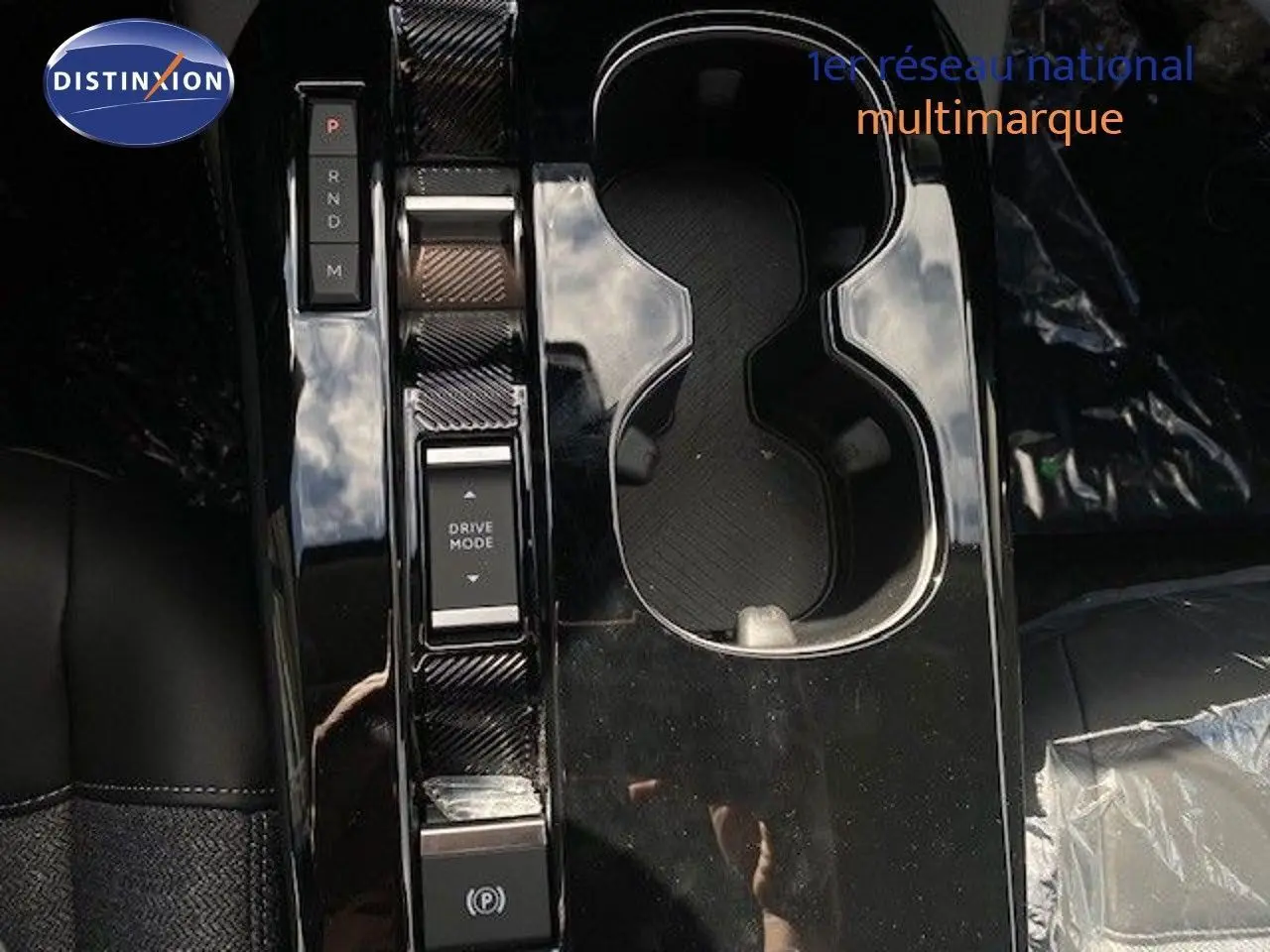 Vue rapprochée de la console centrale noire brillante avec commandes de boîte auto et porte-gobelets du Citroën C5 X gris Thorium.