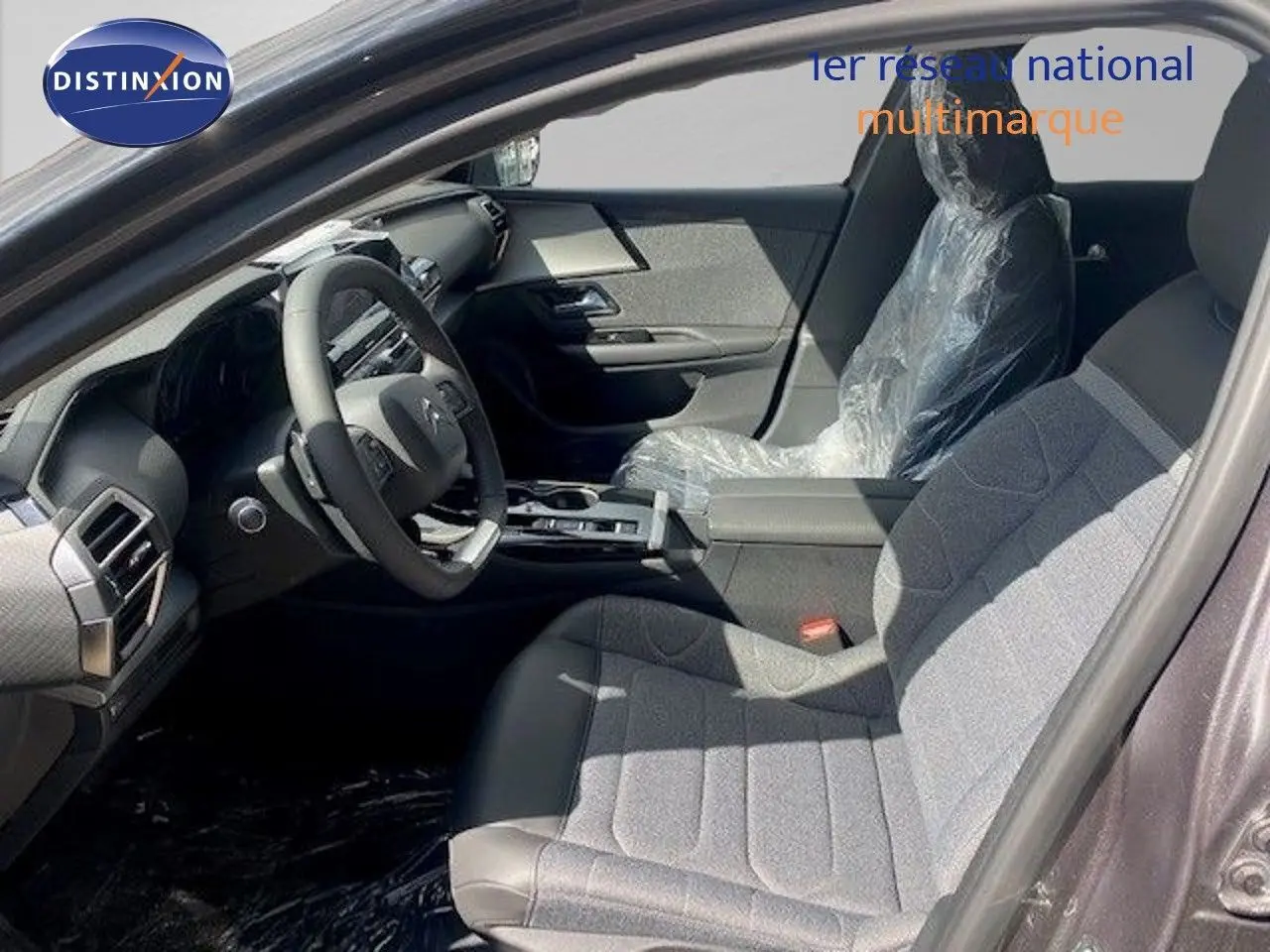 Intérieur avant droit de la Citroën C5 X 2023 gris Thorium, sièges tissu et cuir protégés par film plastique.