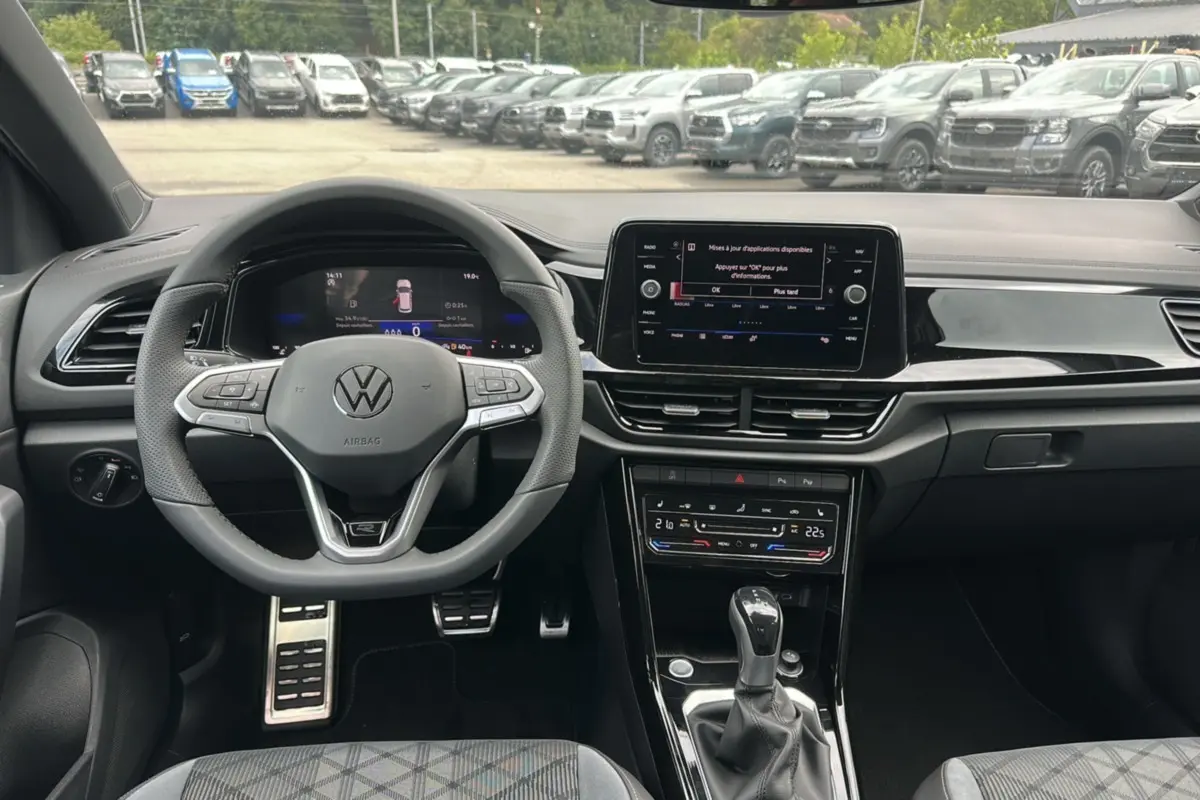 Vue intérieure du tableau de bord et volant du Volkswagen T-Roc gris pyrite 2025 en version R-Line Black.