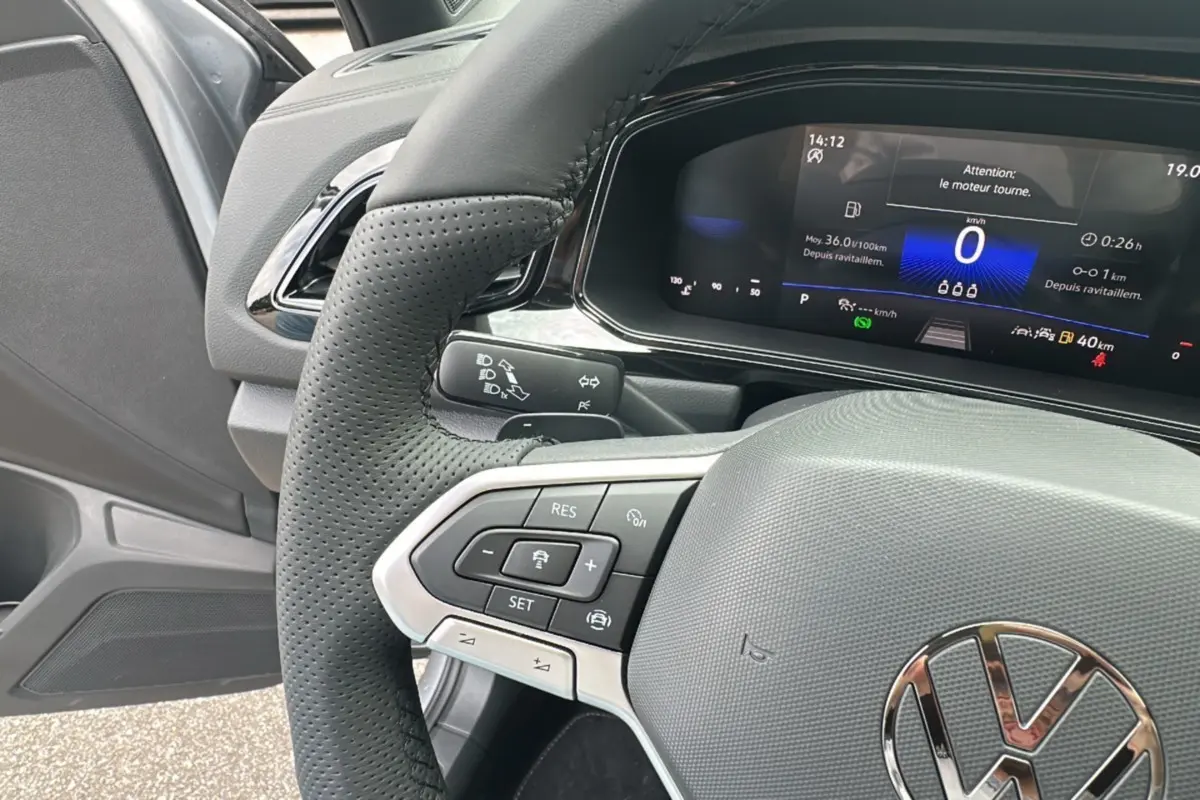 Gros plan sur le volant perforé et le tableau de bord numérique du Volkswagen T-Roc R-Line Black gris pyrite 2025.