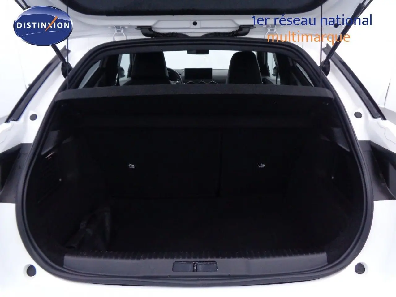 Coffre ouvert vu de l'arrière d'un DS3 Crossback blanc banquise, montrant l'espace de chargement intérieur noir.