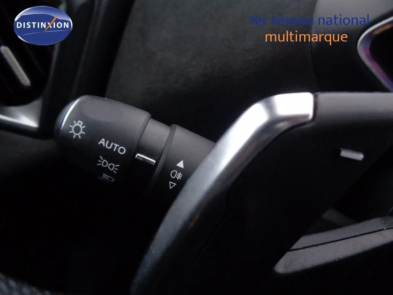 Gros plan sur la commande des feux automatiques et le volant partiellement visible d’un DS3 Crossback blanc banquise.