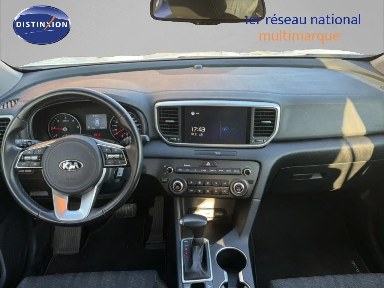 Vue intérieure du tableau de bord du Kia Sportage 2021, volant à gauche, console centrale avec écran tactile et levier de boîte automatique.