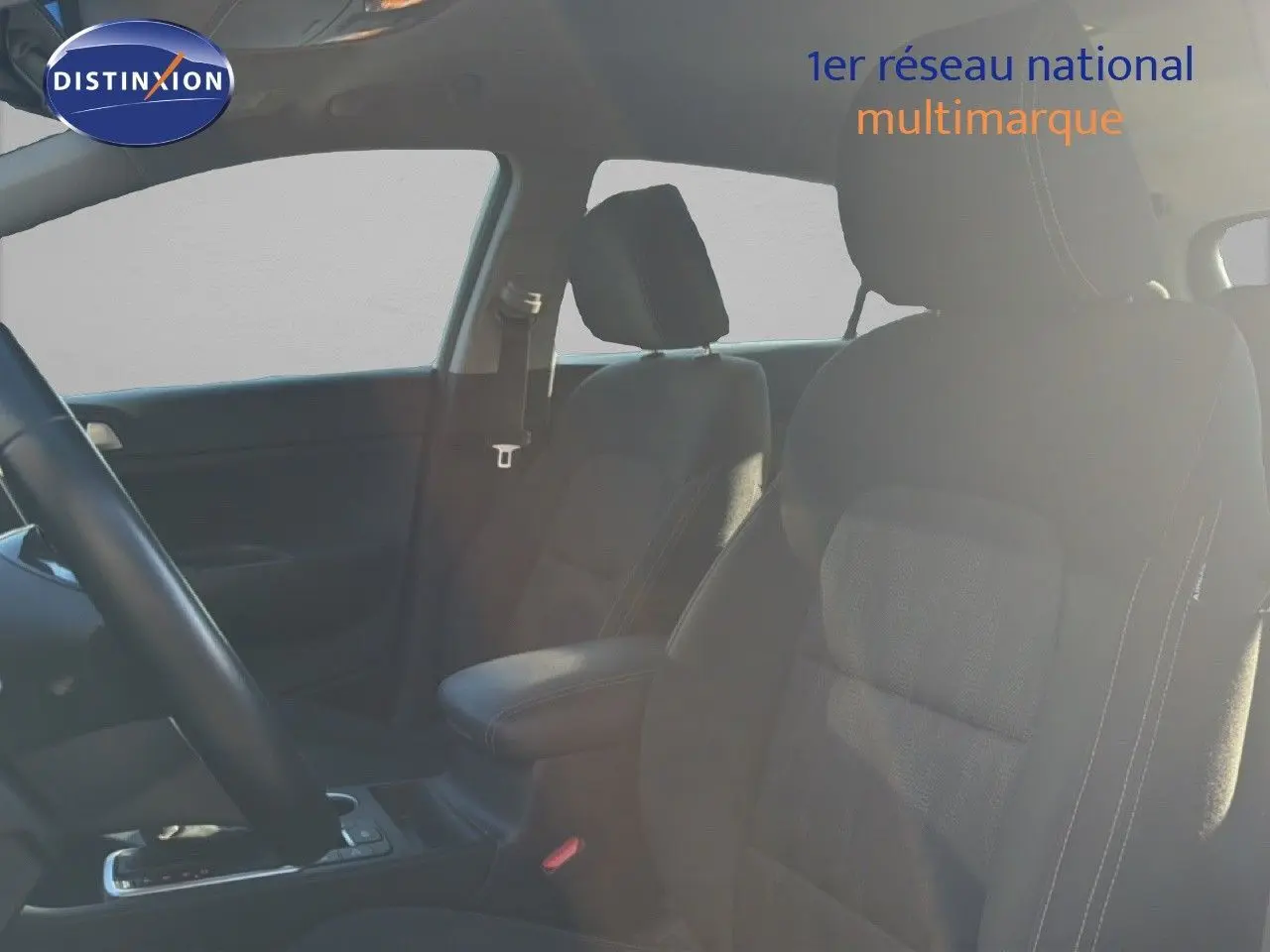 Vue intérieure montrant les sièges avant en tissu noir du Kia Sportage 2021, avec accoudoir central et volant partiel visible.