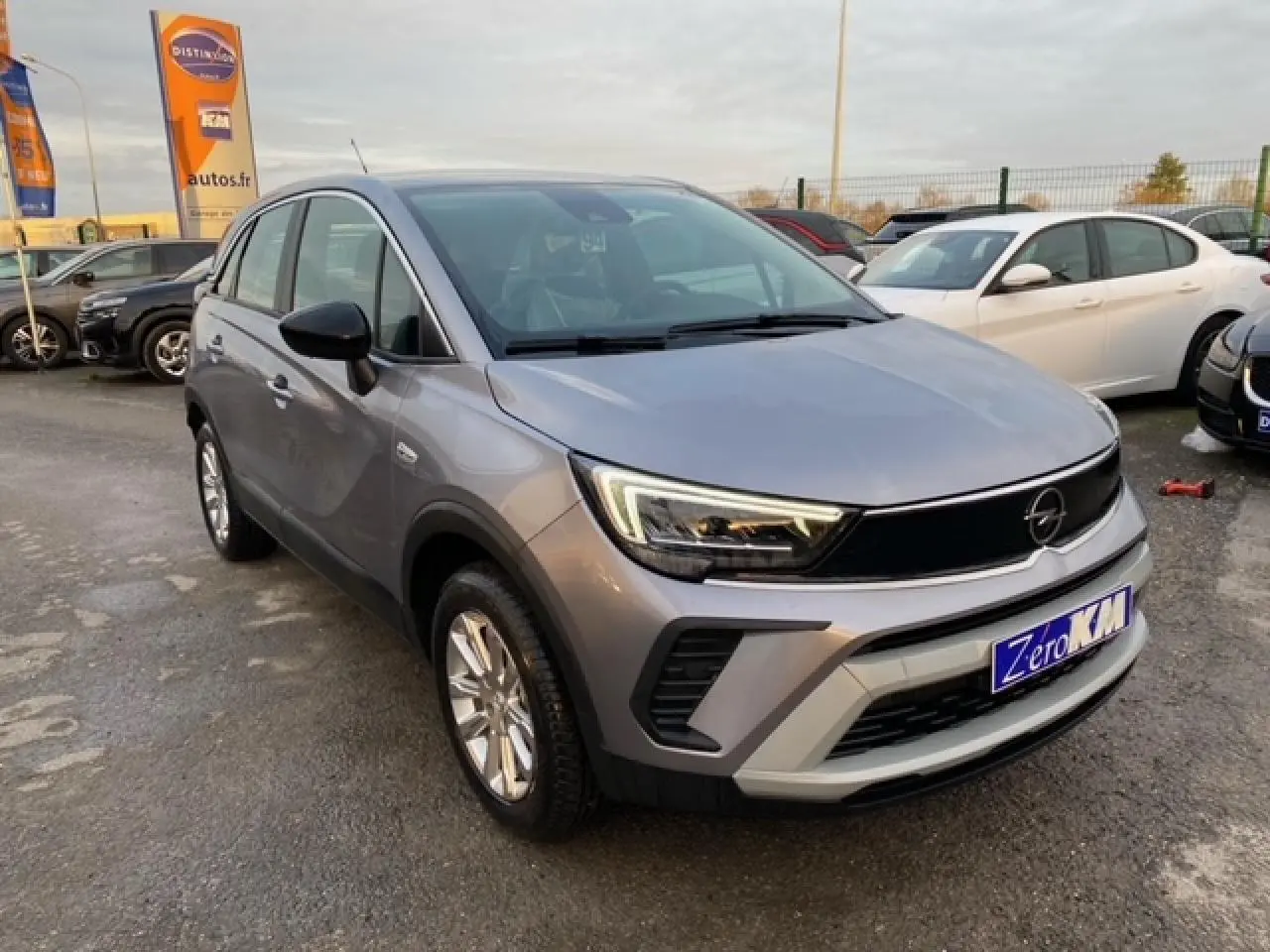 Opel Crossland gris alu en 3/4 avant droit, avec coques de rétroviseurs noires et jantes alliage 16 pouces.