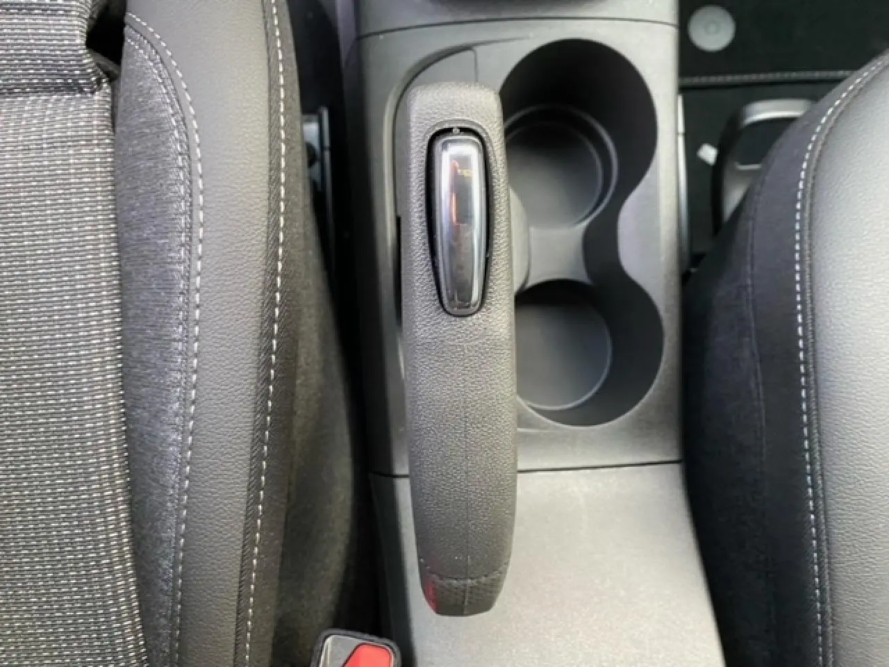 Vue plongeante sur le frein à main et porte-gobelets entre les sièges avant noirs de l’Opel Crossland gris alu.