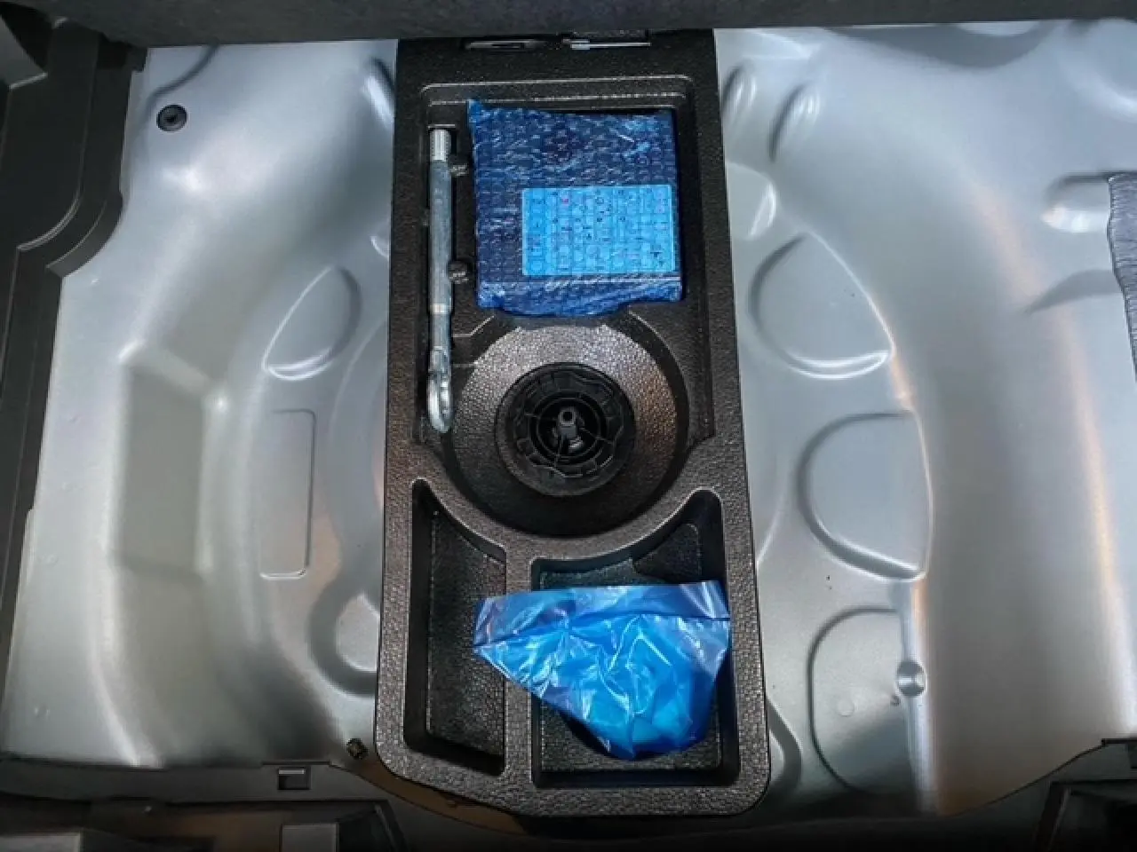 Coffre ouvert de l’Opel Crossland gris alu 2022, montrant le rangement sous plancher avec outils et accessoires en mousse noire.