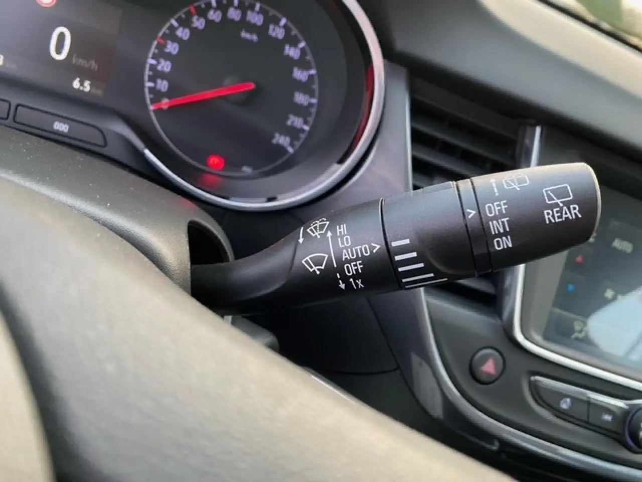 Gros plan sur la commande des essuie-glaces à gauche du volant dans l’habitacle d’un Opel Crossland gris alu 2022.