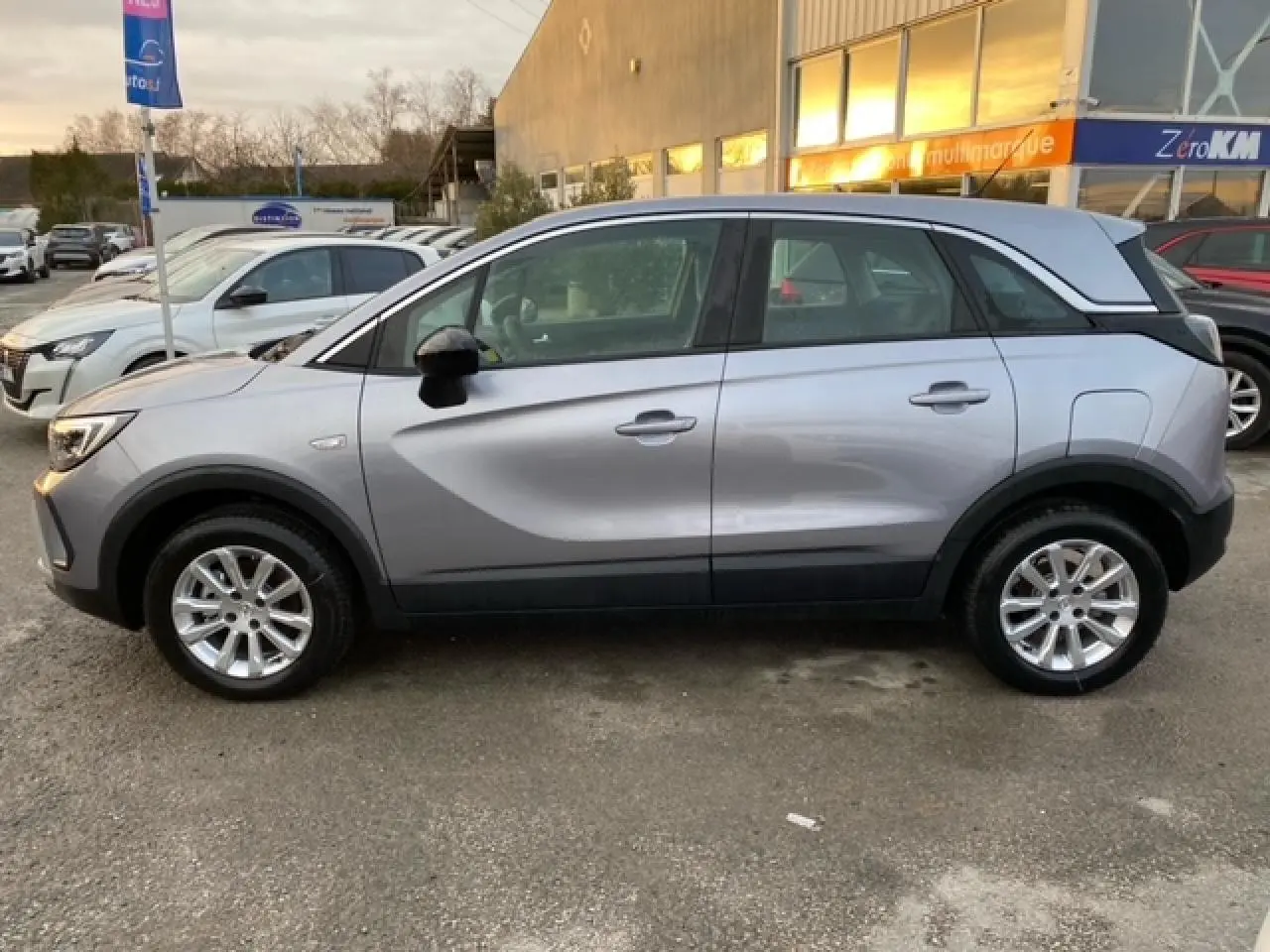 Vue de profil côté gauche d’un Opel Crossland gris alu 2022 avec coques de rétroviseurs noires et jantes alliage 16 pouces.