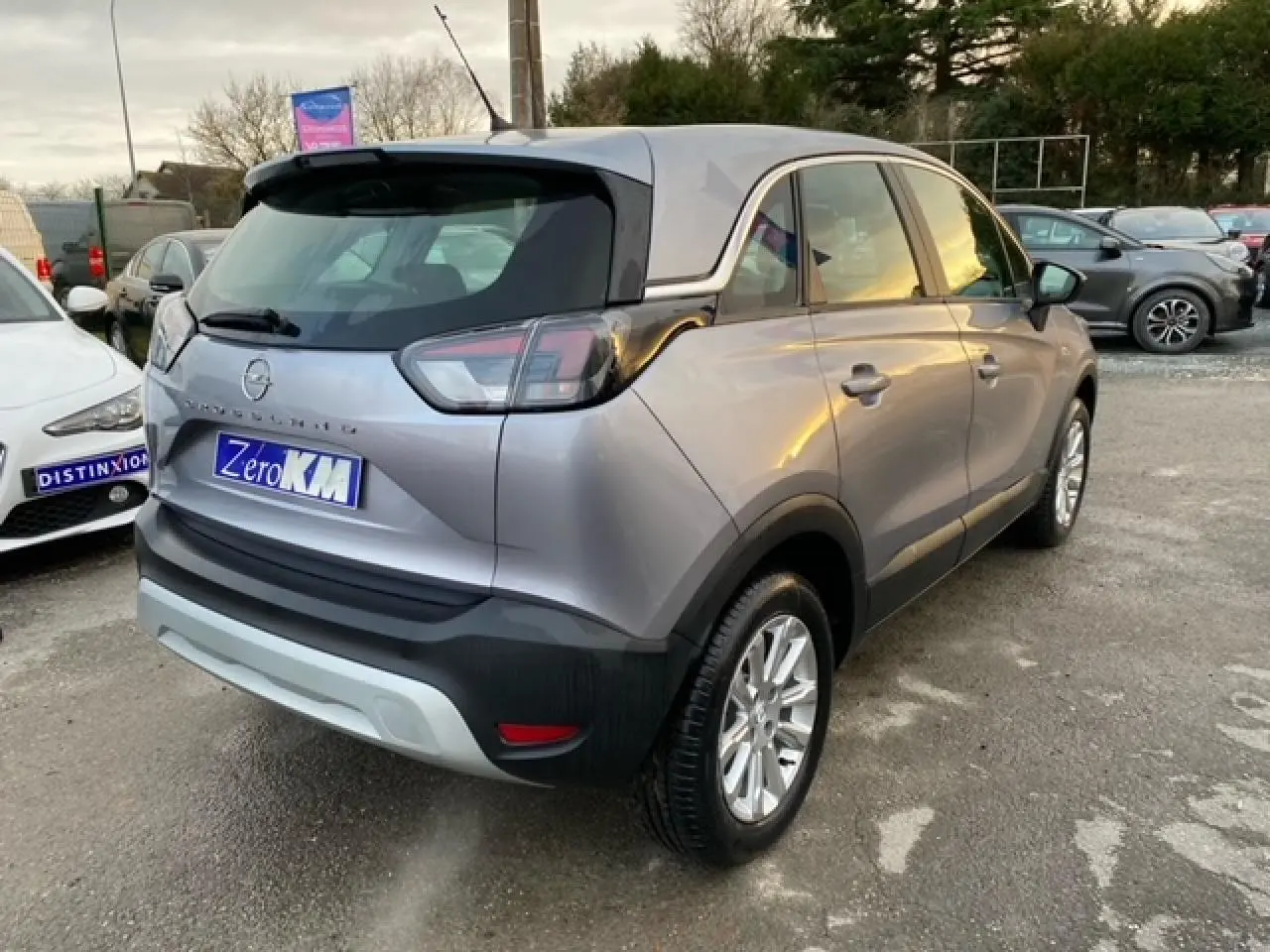 Opel Crossland gris alu en 3/4 arrière droit, avec coques de rétroviseurs noires et jantes alliage 16 pouces.