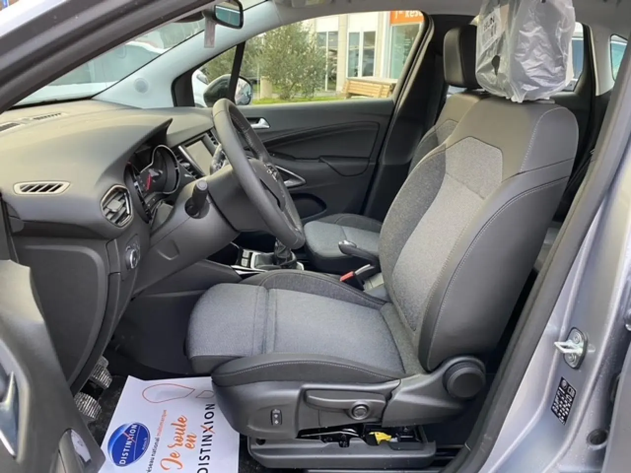 Vue intérieure côté conducteur de l'Opel Crossland gris alu 2022, montrant siège tissu et tableau de bord moderne.
