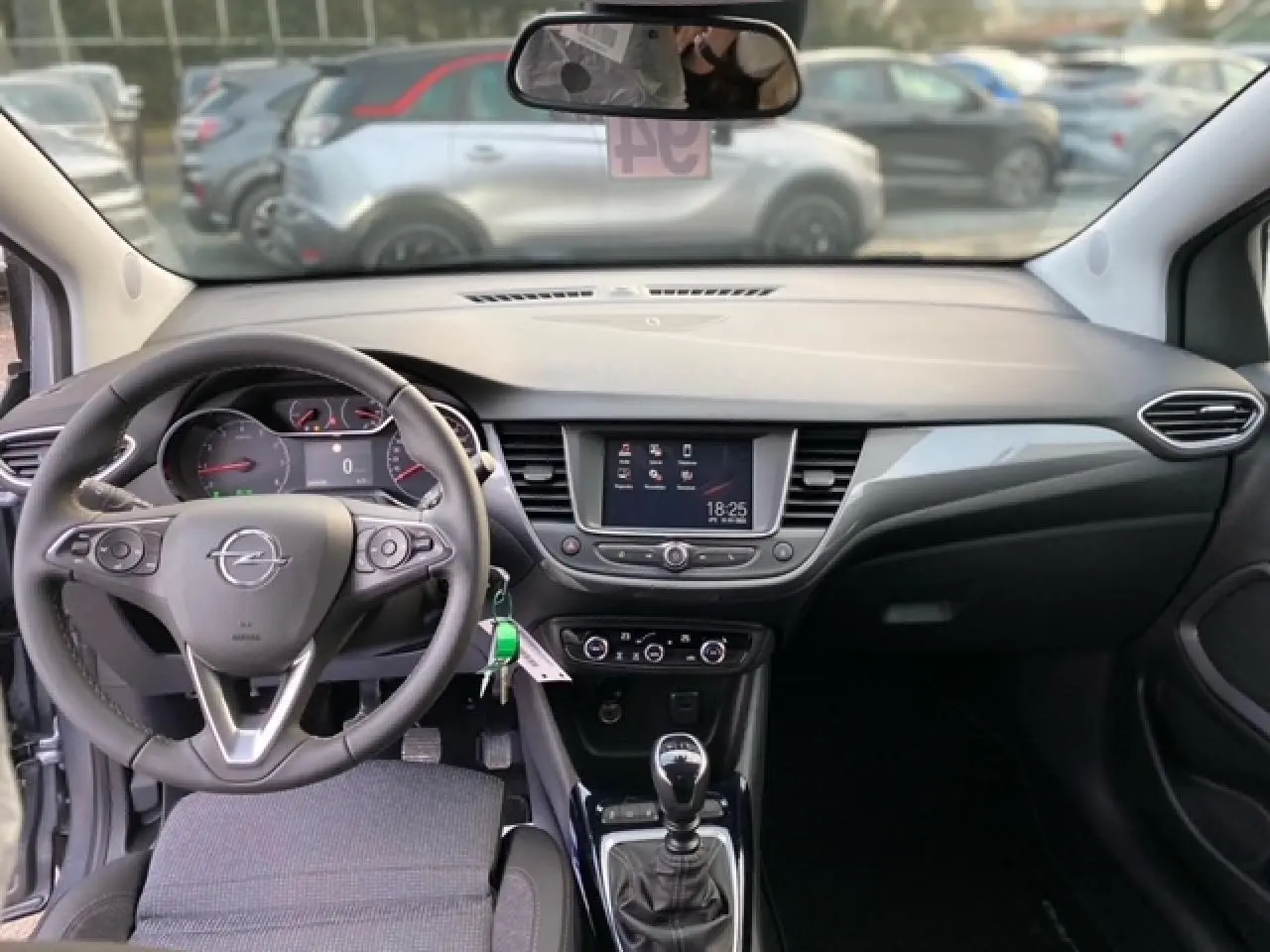 Intérieur Opel Crossland 2022 vu de face, tableau de bord noir avec écran tactile et levier de vitesse manuel.