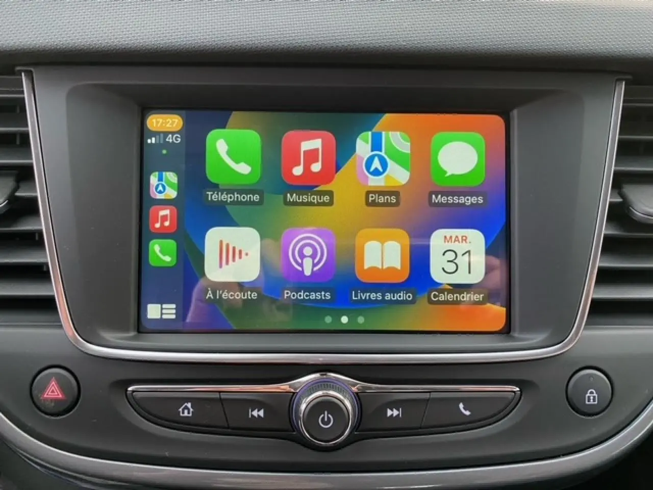Écran tactile central de l’Opel Crossland 2022 affichant Apple CarPlay avec icônes colorées, entouré de commandes noires.