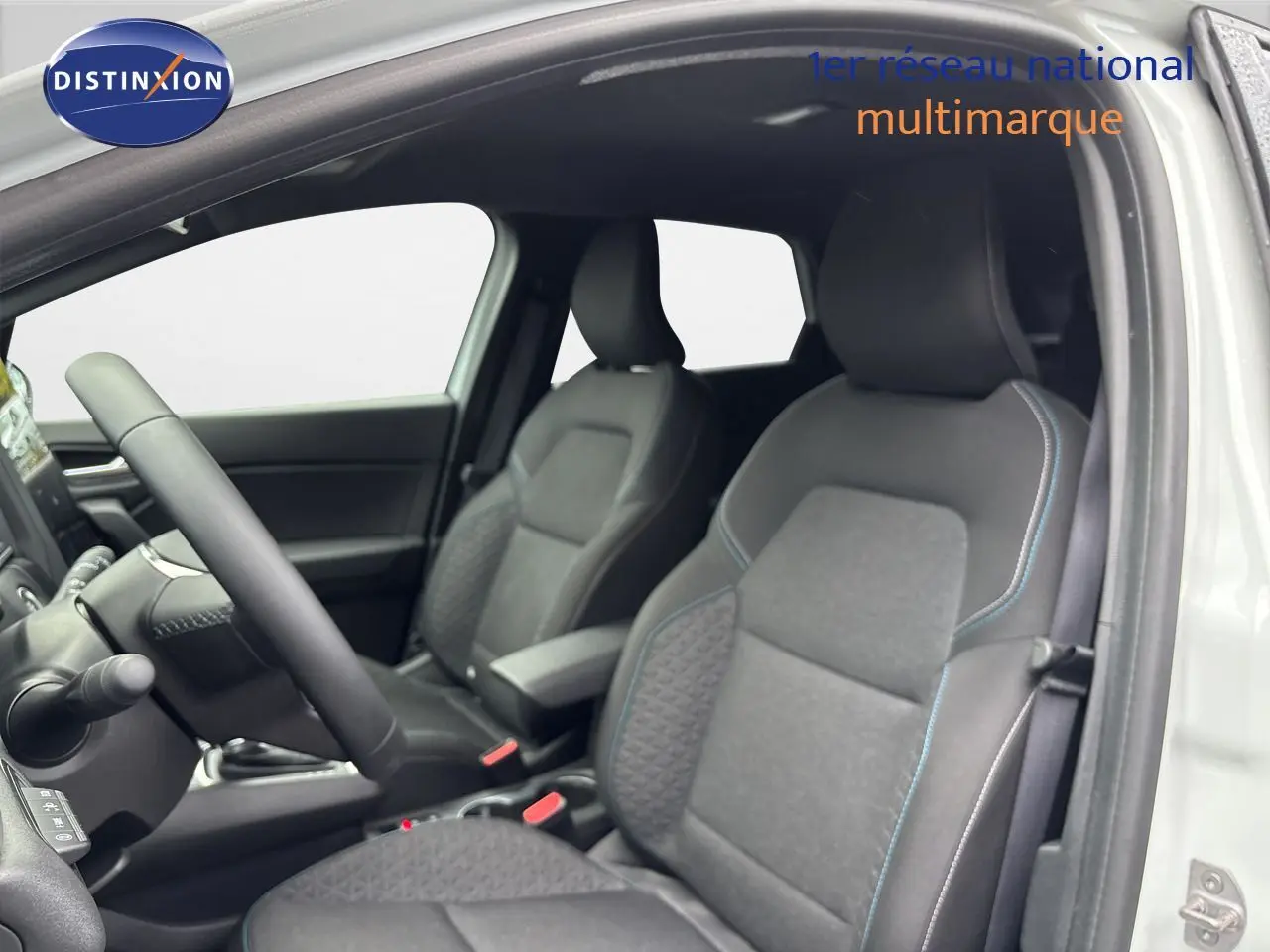 Intérieur de la Renault Symbioz 2025, vue côté gauche sur les sièges tissu noir avec surpiqûres bleues et volant.