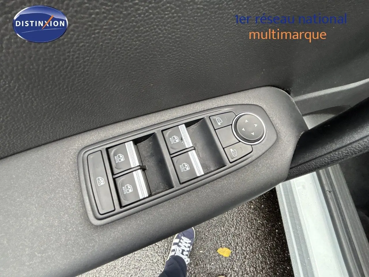 Gros plan sur les commandes de lève-vitres et rétroviseurs sur la porte intérieure d'une Renault Symbioz blanc nacré.