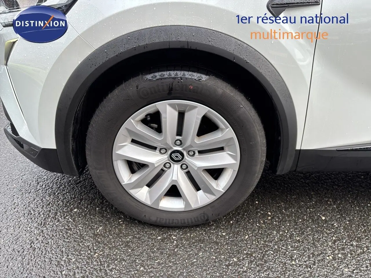 Gros plan sur la roue avant gauche d’un Renault Symbioz blanc nacré, avec jante alliage et logo central visible.