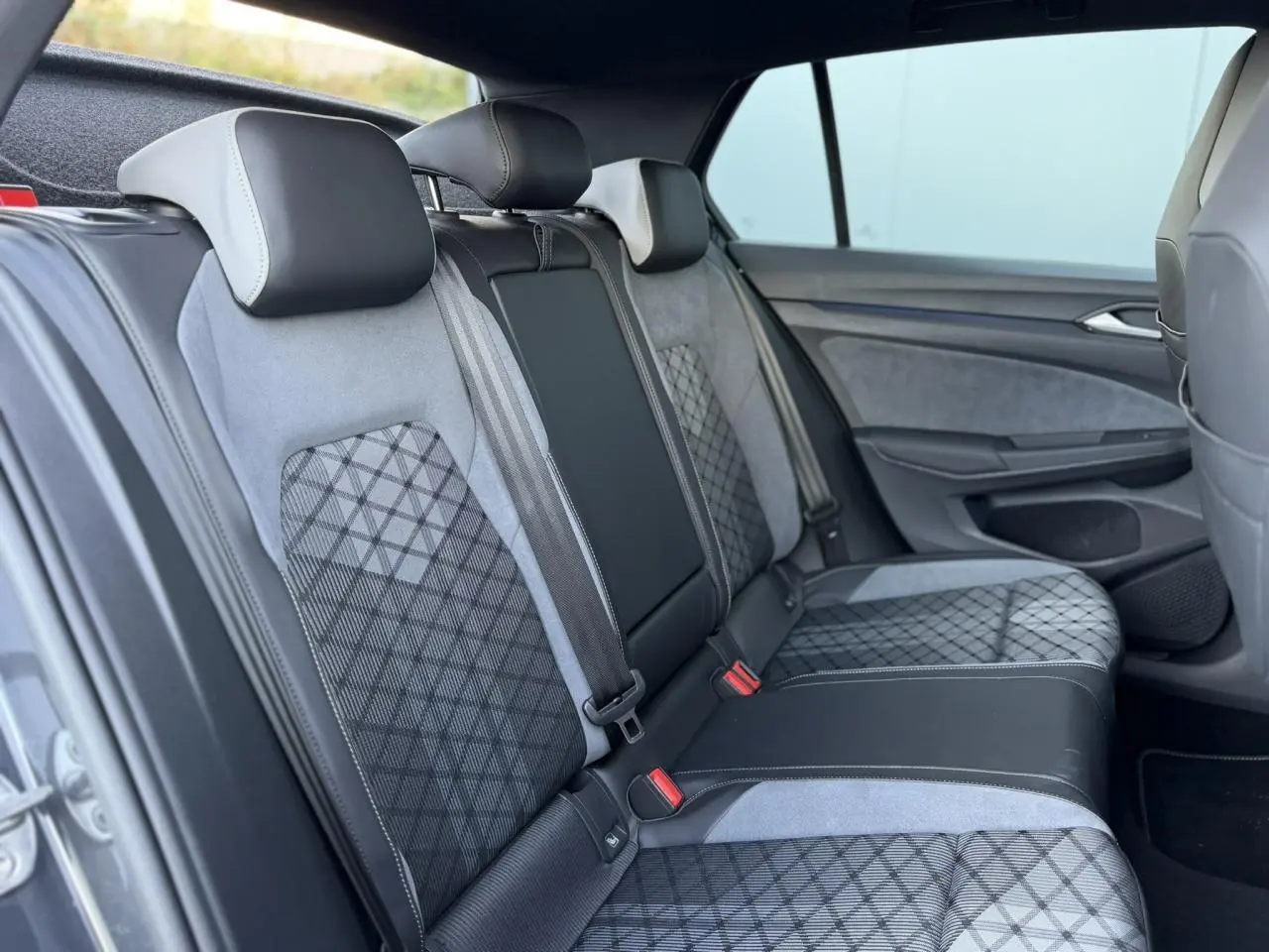 Vue latérale droite de l’arrière intérieur de la Volkswagen Golf 8 R-Line 2024 avec sellerie tissu gris et motifs géométriques.
