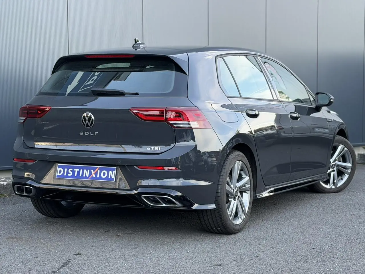 Volkswagen Golf 8 eTSI R-Line gris Urano vue 3/4 arrière droit avec jantes alliage et double sortie d’échappement.
