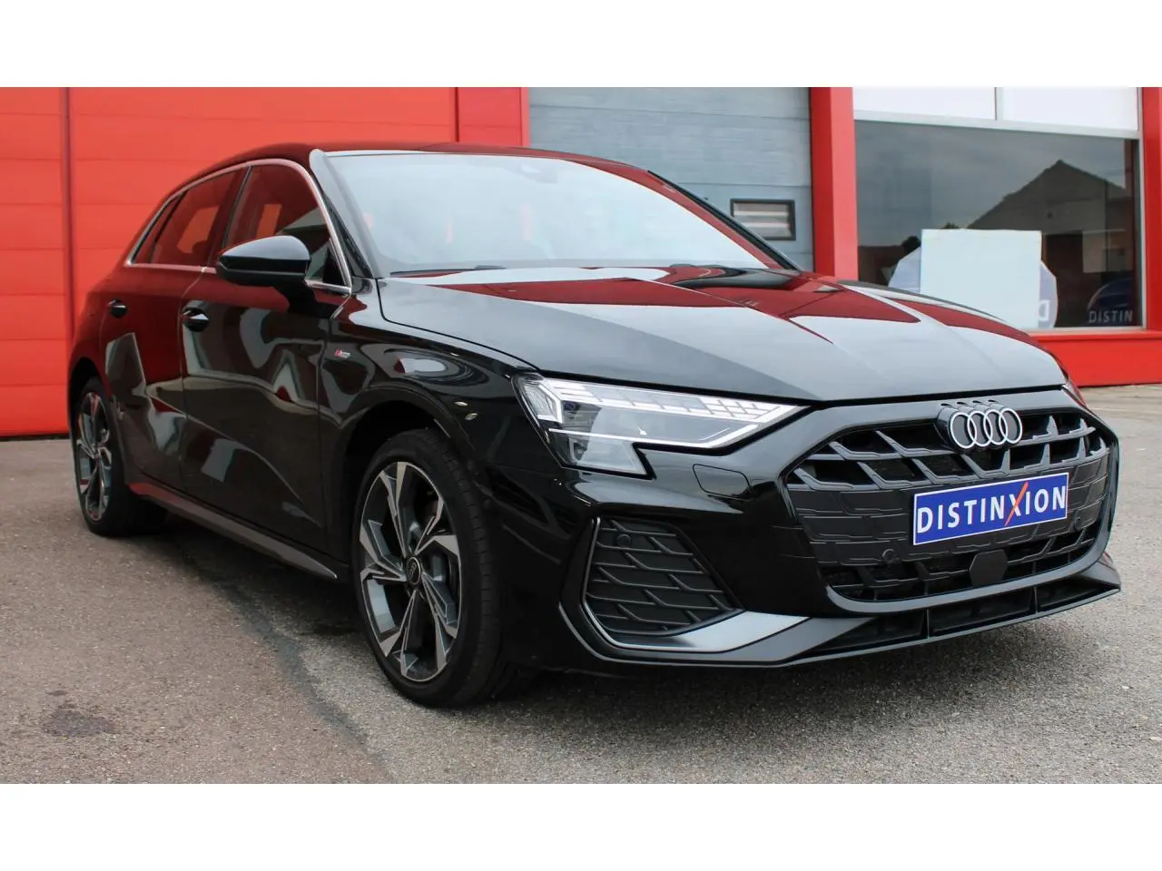 Audi A3 Sportback noir mito metal vue 3/4 avant, avec calandre large et jantes alliage 18 pouces gris graphite.