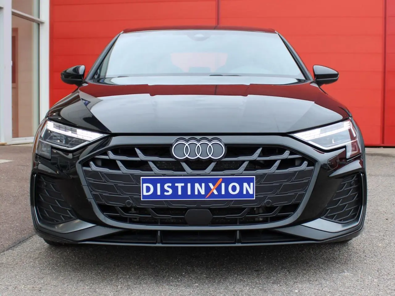 Vue frontale d'une Audi A3 Sportback noire Mito Metal avec calandre hexagonale et phares Matrix LED allumés.
