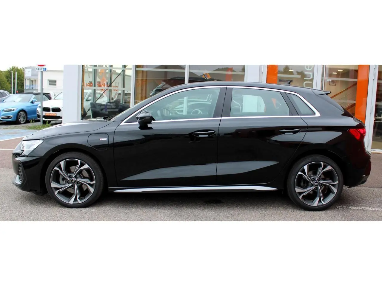 Audi A3 Sportback noir mito metal vue de profil côté gauche, jantes alliage 5 branches en Y et détails S line visibles.