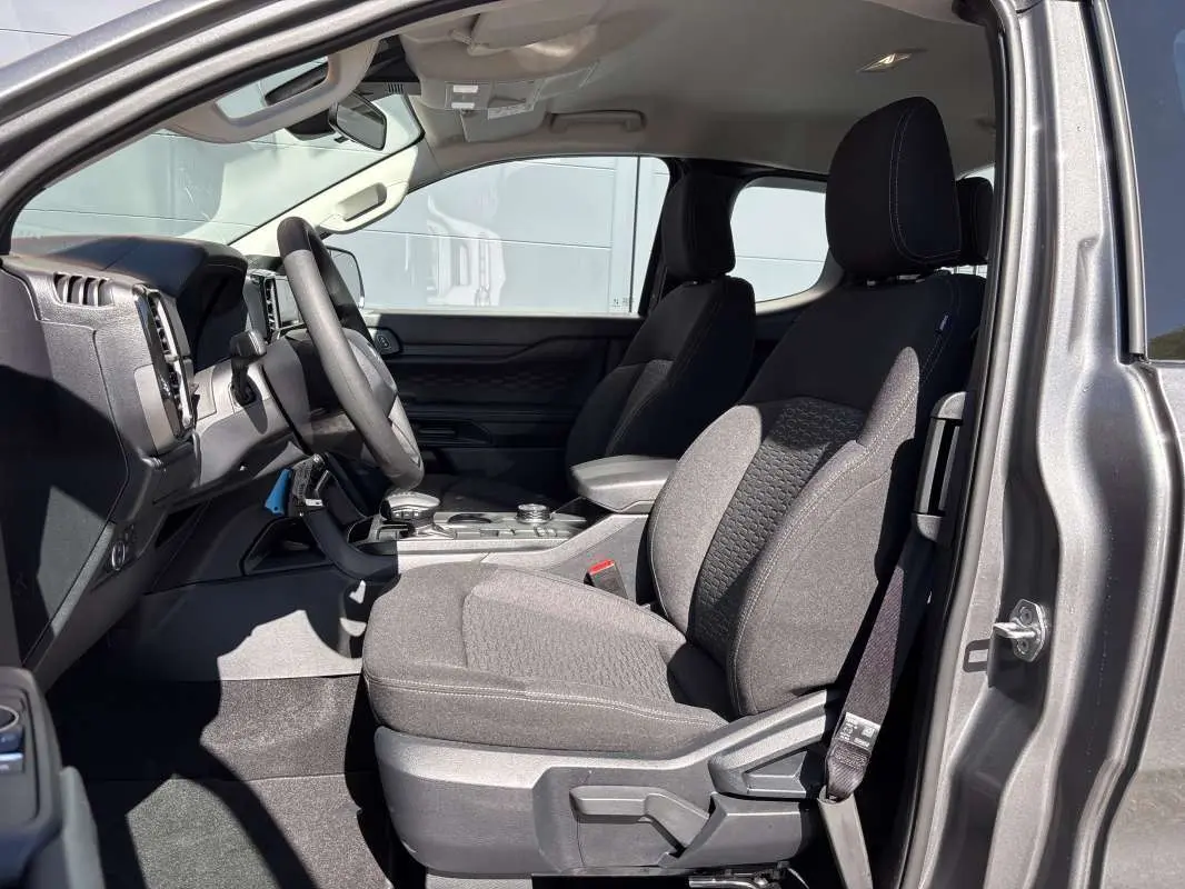Vue intérieure côté conducteur du Ford Ranger gris carbone 2026, montrant les sièges avant et le tableau de bord.