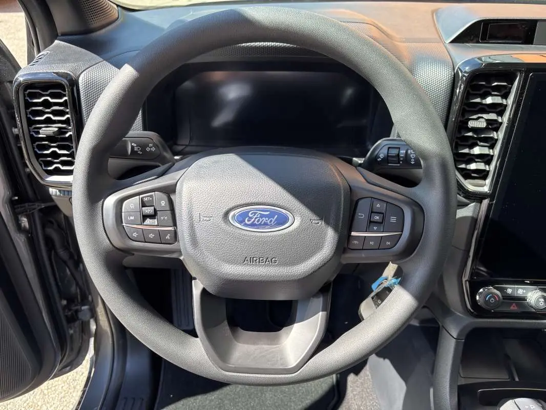 Vue rapprochée du volant cuir multifonctions gris du Ford Ranger 2026 avec tableau de bord et écran tactile visibles.