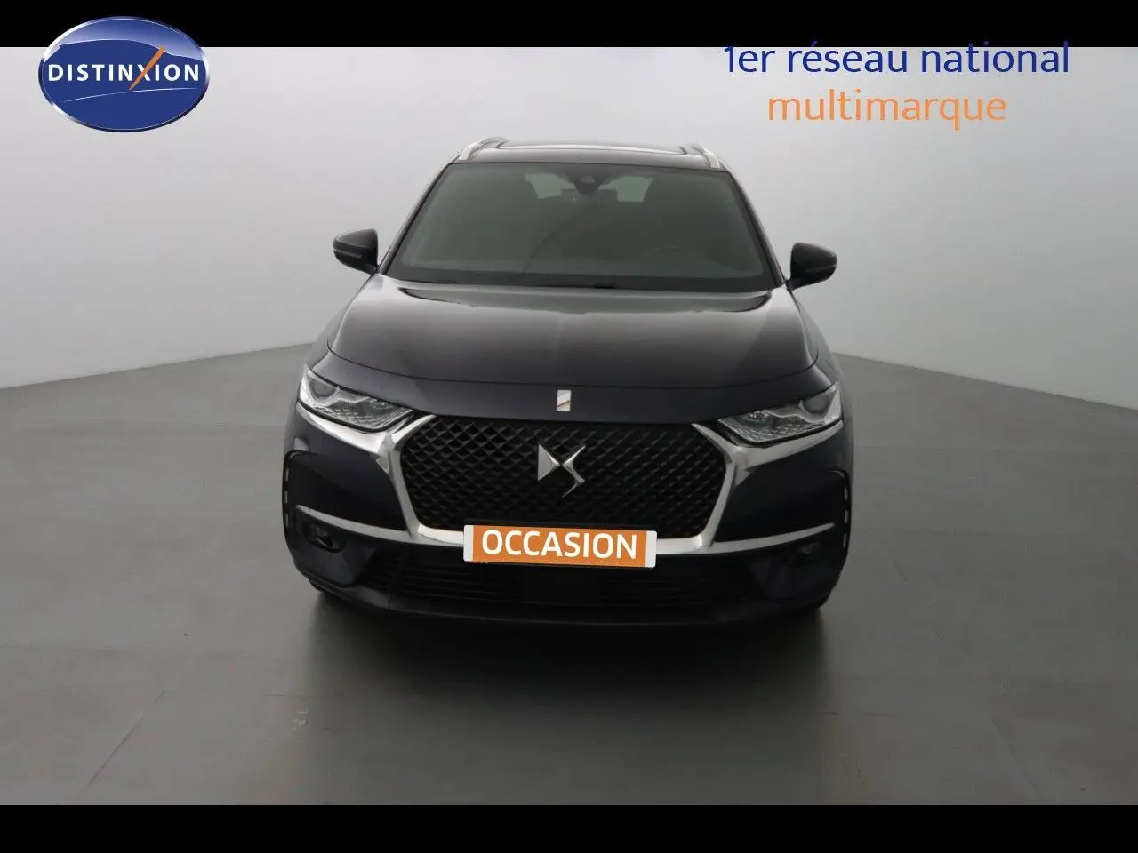 Vue frontale d'un DS7 Crossback hybride bleu encre métal avec calandre distinctive et phares LED fins.