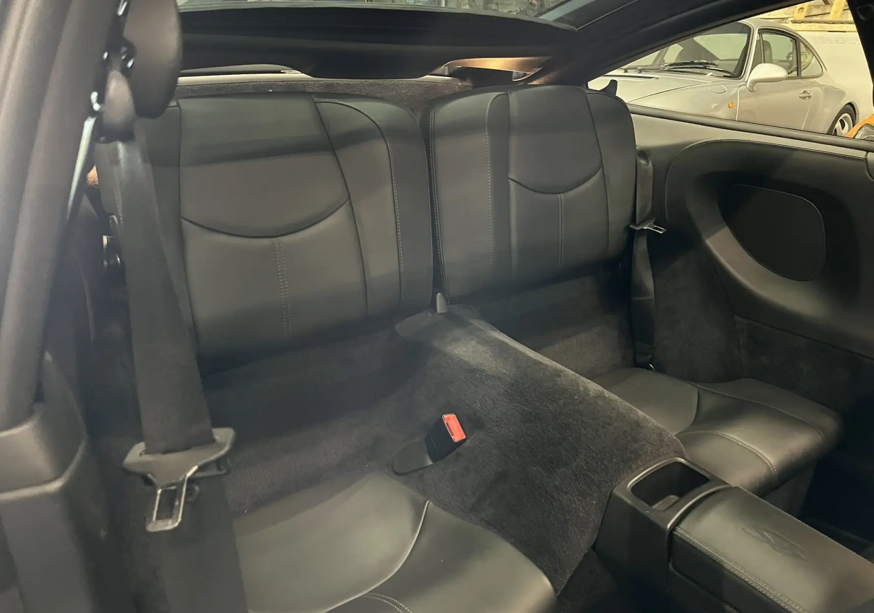 Vue intérieure arrière des sièges en cuir noir de la Porsche 911 Targa 997 Carrera 4S, avec accoudoir central et ceinture de sécurité.