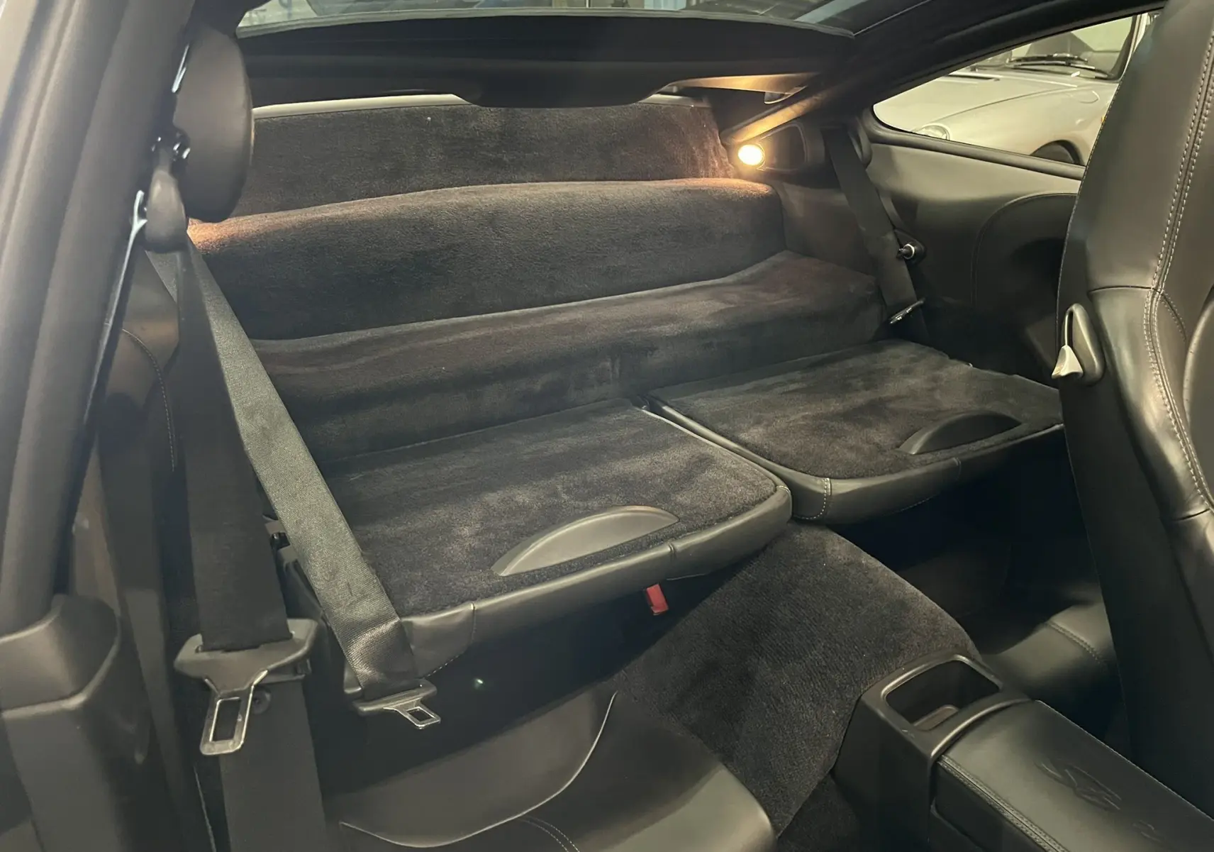 Vue intérieure arrière de la Porsche 911 Targa 997 Carrera 4S 2006, sièges arrière rabattus en cuir noir.