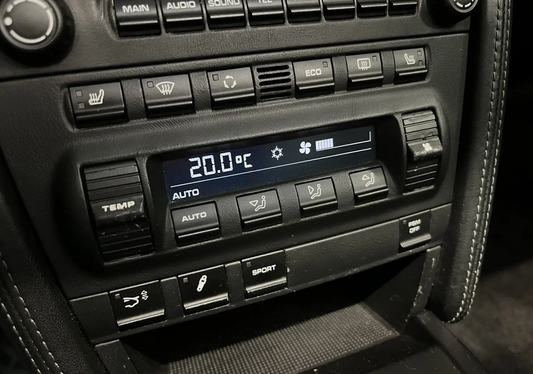 Gros plan sur la console centrale noire du Porsche 911 Targa 997 Carrera 4S, affichant la climatisation à 20°C et les commandes sport.