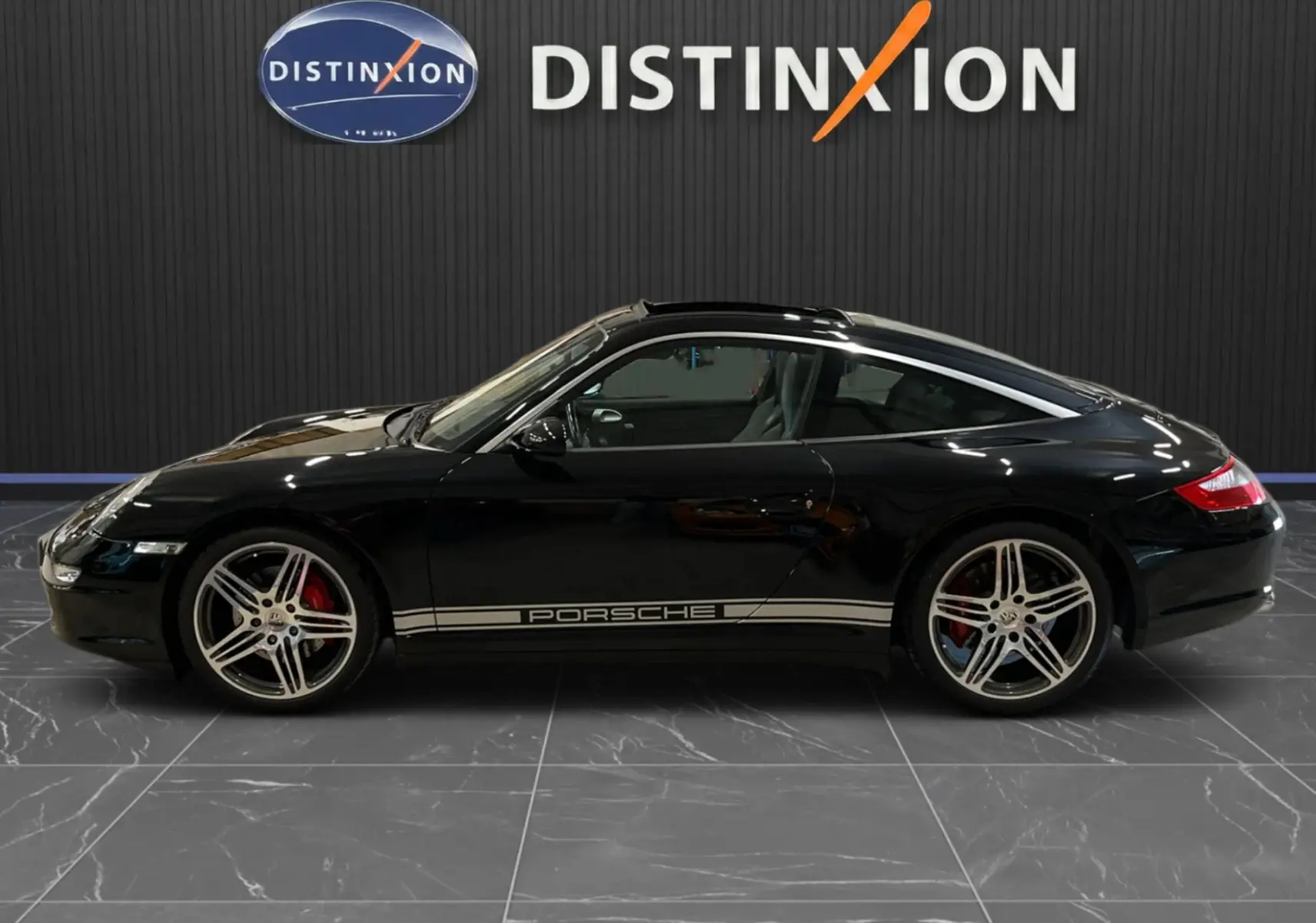 Profil droit d'une Porsche 911 Targa 997 Carrera 4S noire métallisée avec jantes Turbo 19 pouces et bandeau latéral Porsche argenté.