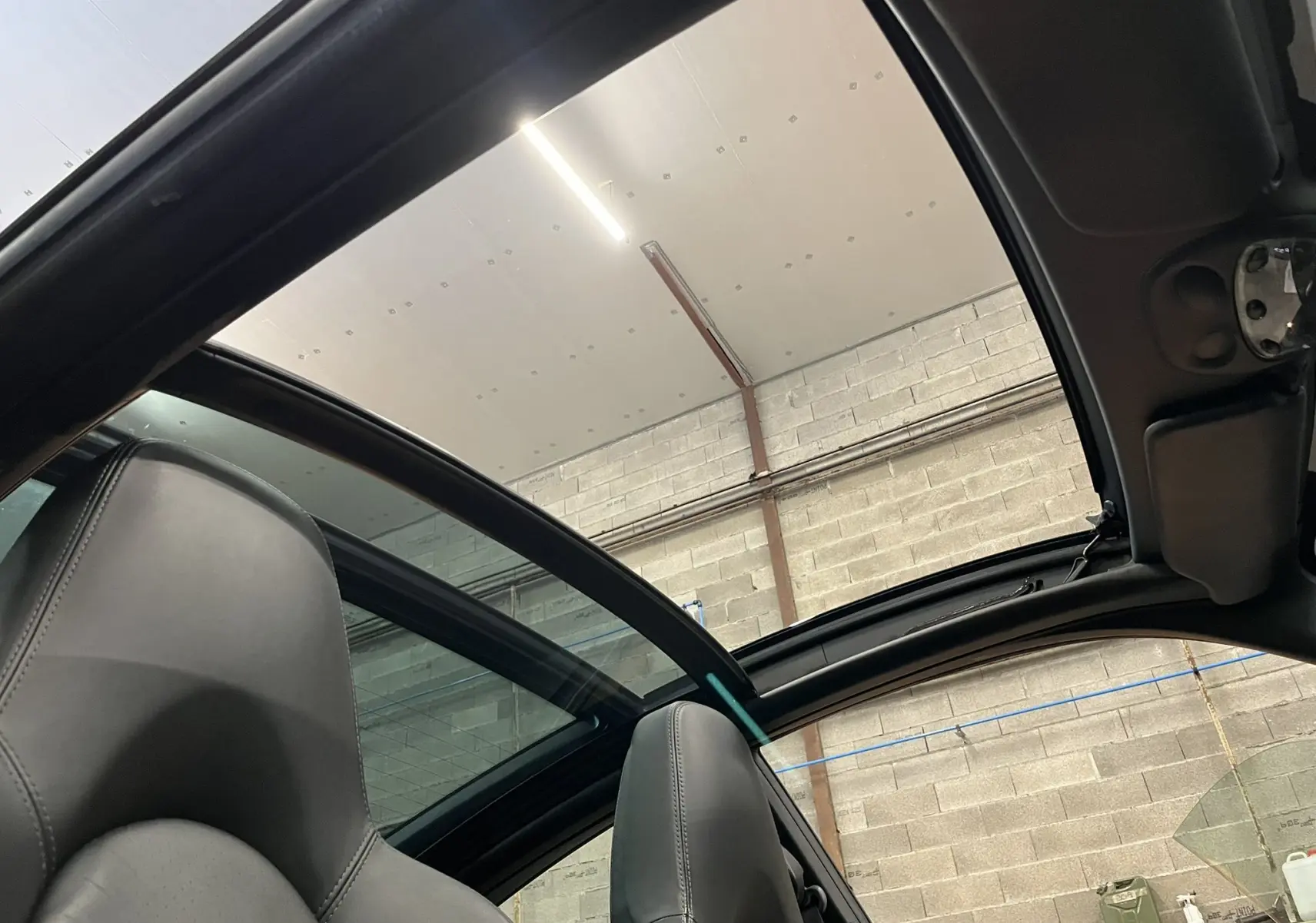 Vue intérieure montrant le toit ouvrant panoramique et les sièges en cuir noir d'une Porsche 911 Targa 997 Carrera 4S 2006.