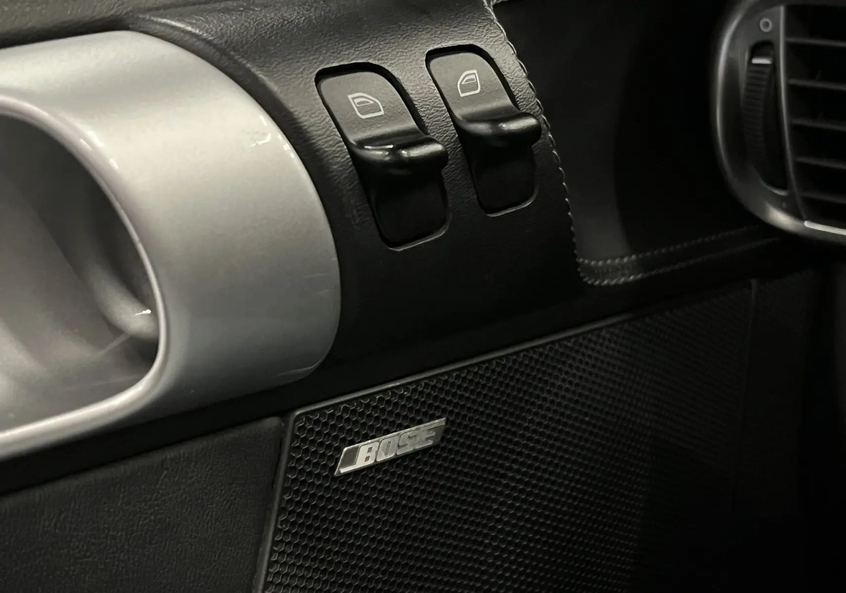 Détail intérieur côté conducteur de la Porsche 911 Targa 997 Carrera 4S 2006, avec commandes de vitres et enceinte Bose noire.