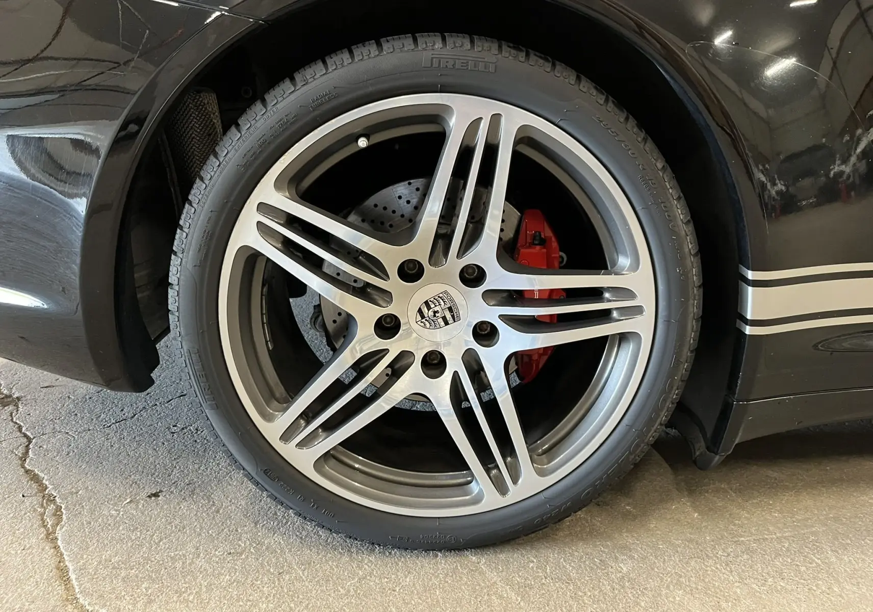 Gros plan sur la jante Turbo 19 pouces bi-ton d’une Porsche 911 Targa 997 Carrera 4S noire avec étrier de frein rouge.